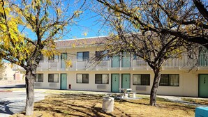 A building with multiple rooms, each with a door and windows, and a small outdoor seating area with tables and benches. - Motel 9 Las Cruces (Las Cruces)