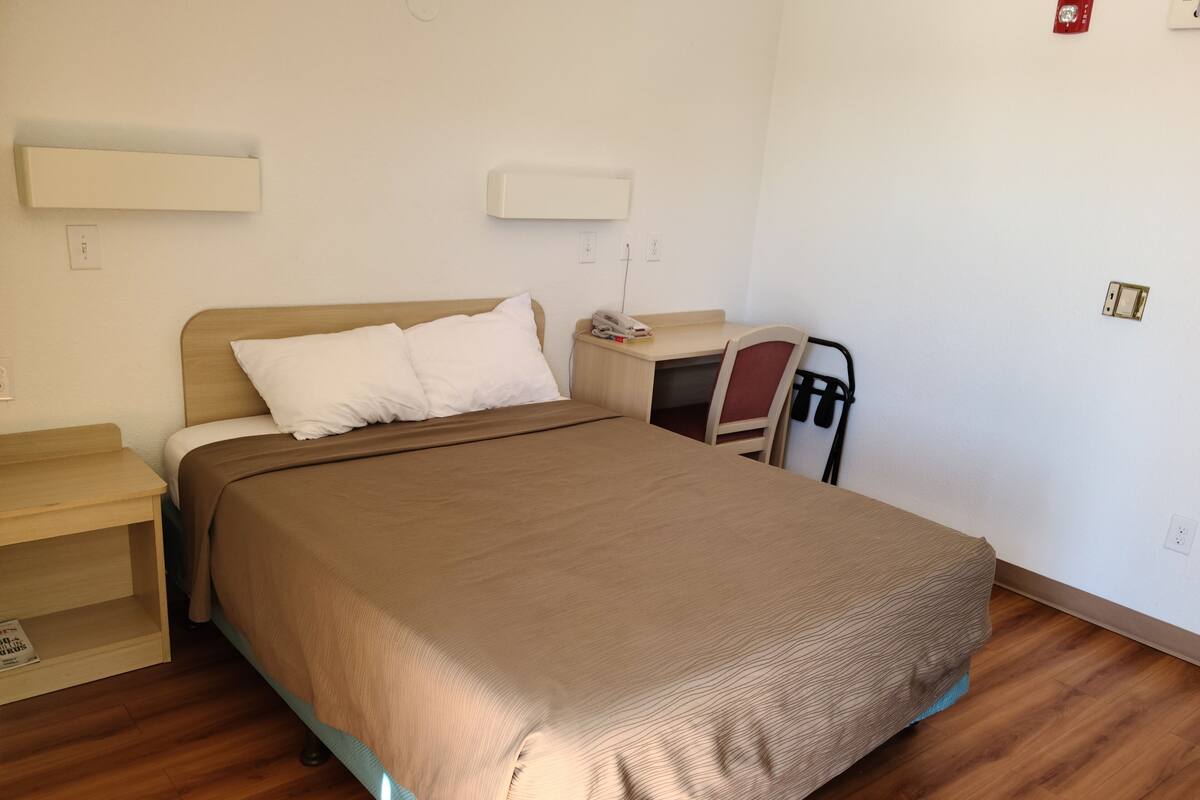 A bedroom with a bed, bedside table, and a chair.