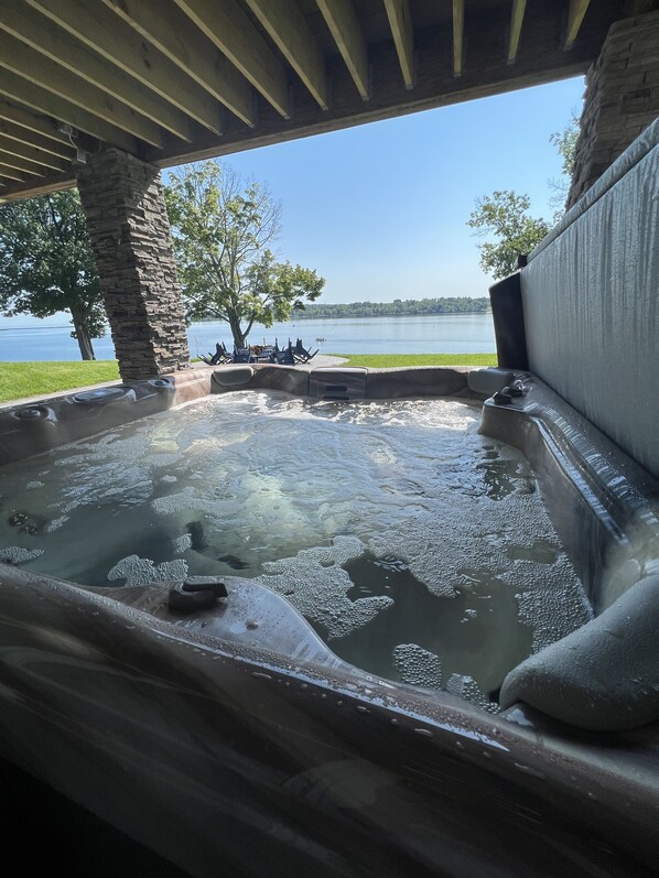 Uma banheira de hidromassagem com um pilar de pedra e vista para um lago.