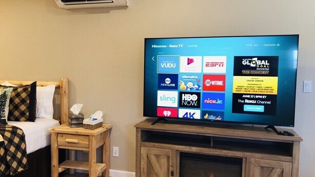 A television on a wooden stand with a digital menu displaying various streaming services. - Riverside Cabin 2 - (Brand New Construction) (Grants Pass)