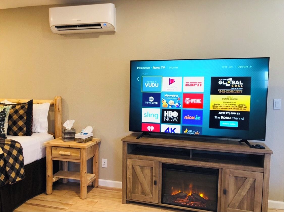 A television on a wooden stand with a digital menu displaying various streaming services.