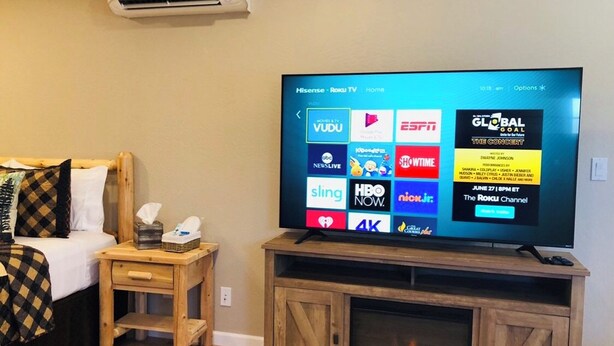 A television on a wooden stand with a digital menu displaying various streaming services. - Riverside Cabin 2 - (Brand New Construction) (Grants Pass)
