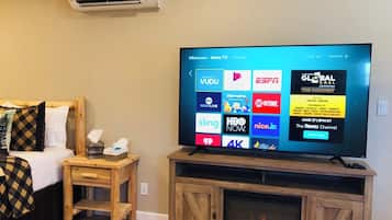 Een televisie op een houten standaard met een digitaal menu waarop diverse streamingdiensten worden getoond.