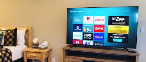 Een televisie op een houten standaard met een digitaal menu waarop diverse streamingdiensten worden getoond.