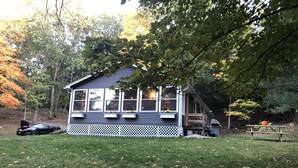 Ett hus med en veranda, en gräsmatta och en bil parkerad i närheten.