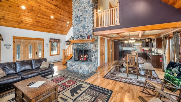 A spacious living area with a stone fireplace, wooden ceiling, and a cozy seating arrangement.