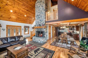 A spacious living area with a stone fireplace, wooden ceiling, and a cozy seating arrangement. - Riverfront Cabin|Fireplace|Fire pit | White Mountains| Hiking (Twin Mountain)