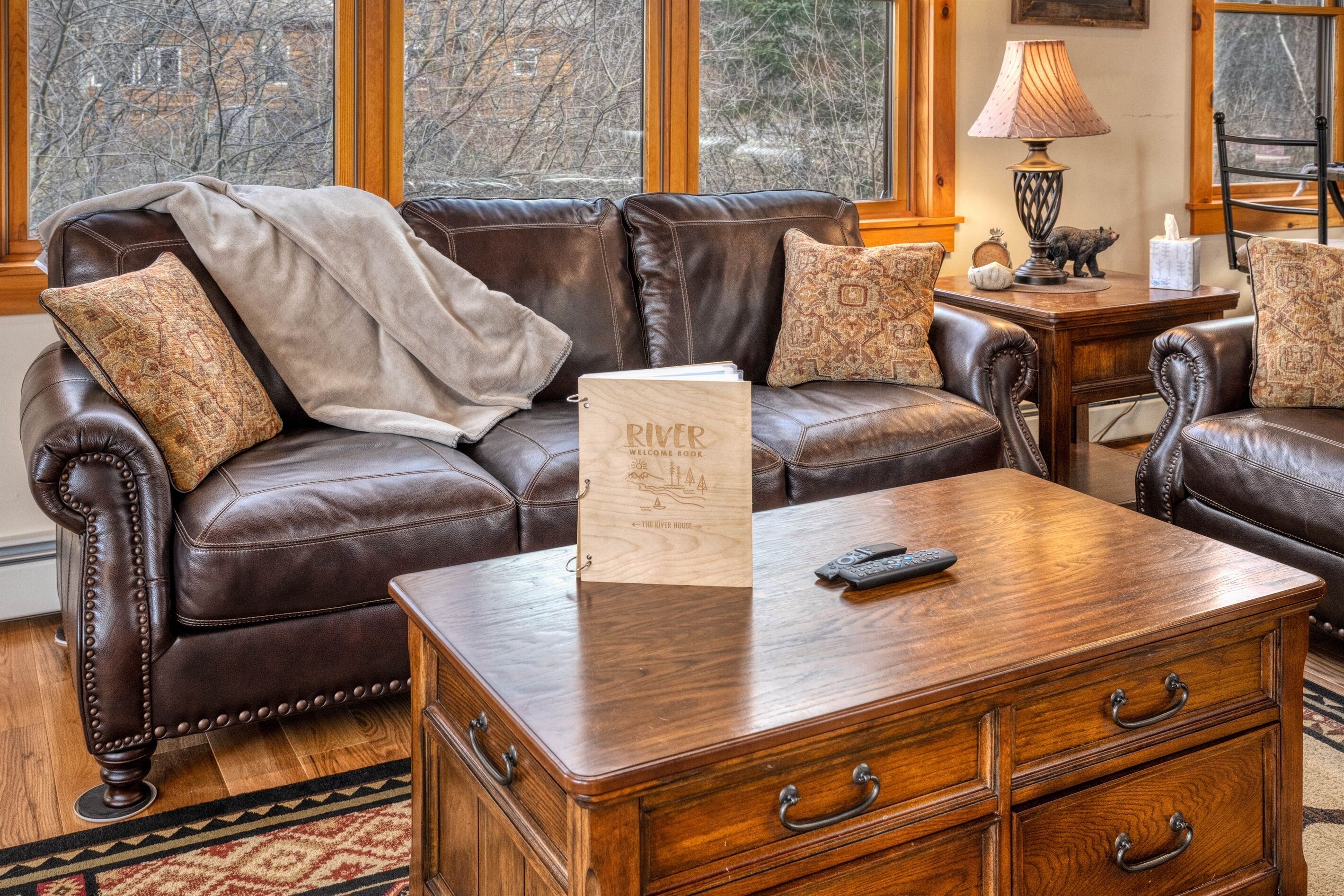 Un canapé en cuir, un livre d’accueil, une table basse en bois et une lampe.