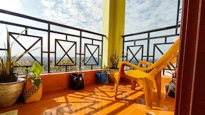 Un balcon agrémenté de plantes en pot, une chaise jaune et une vue sur le paysage urbain.