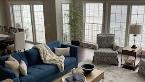 A spacious living room with a blue sofa, a coffee table, and a potted plant. - Relax lakeside at our spacious Geneseo house on  Conesus Lake (Conesus)