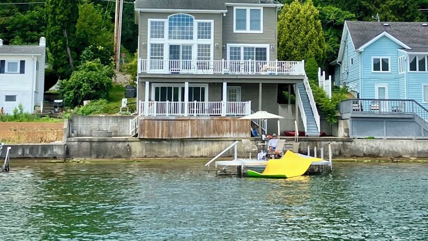 A two-story house with a balcony, a dock, and a small boat. - Relax lakeside at our spacious Geneseo house on  Conesus Lake (Conesus)