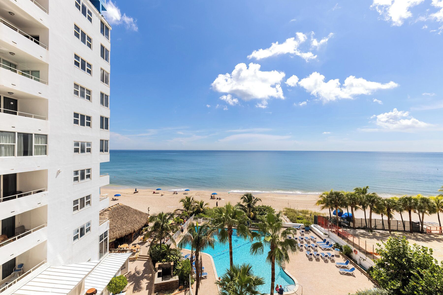A hotel with a pool, beach, and ocean view.