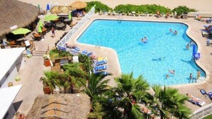 Un espace piscine avec une piscine à l’eau cristalline, des chaises longues, des parasols et une vue sur l’océan.