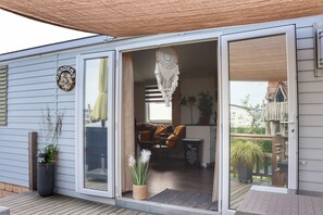 Una casa moderna con una porta a vetri scorrevoli che dà su un soggiorno con un divano e un portafortuna decorativo appeso.