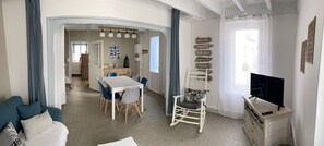 A spacious living area with a dining table, blue chairs, a white rocking chair, a TV on a wooden stand, and a wall with nautical signs. - La Chaume, Typical and charming fisherman's house (Les Sables-d'Olonne)
