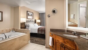 A hotel bathroom with a large bathtub, a separate shower area, a vanity with a sink, and a mirror. - Ski Resort (Vail)