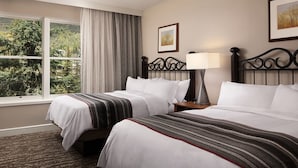A hotel room with two beds, a large window with a view of trees, a framed picture on the wall, and a bedside lamp. - Ski Resort (Vail)