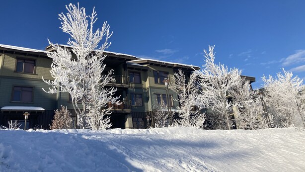 A multi-story building with a snow-covered landscape, featuring a balcony and a visible window.