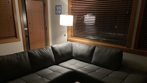 A corner sofa with a small table in front, a window with blinds, and a sign on the wall.