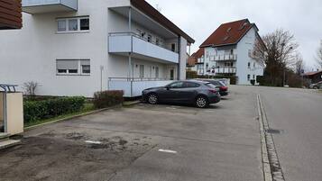 Eine Wohnstraße mit mehrstöckigen Wohngebäuden, einem Parkplatz und parkenden Autos entlang der Seite.