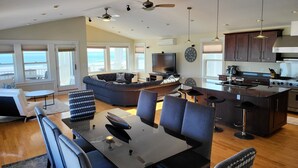 A spacious living area with a large sofa, dining table, and kitchen area.