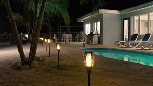 Ein Poolbereich mit Pool, Liegestühlen und einem Grill.