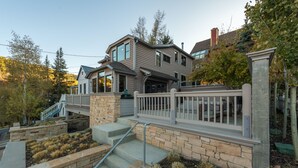 A two-story house with a stone foundation, a covered porch, and a staircase leading to the upper level. - Old Town Private Home by Luxury Mountain Destinations (Park City)