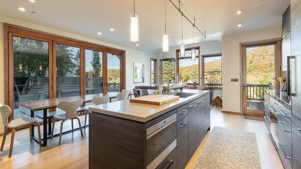 A modern kitchen with a large island, wooden cabinetry, and pendant lighting. - Old Town Private Home by Luxury Mountain Destinations (Park City)