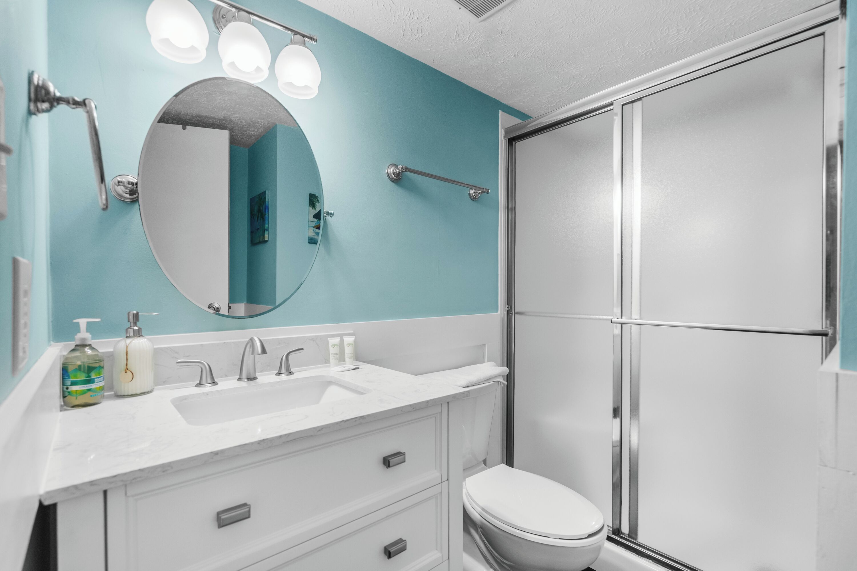 A bathroom with a white sink, a mirror, and a shower enclosure.