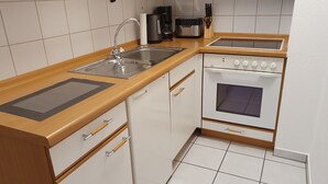Eine kleine Küche mit Spüle, Kaffeemaschine, Toaster und Backofen.