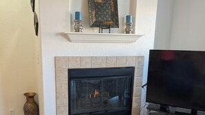 A living room with a fireplace, a flat-screen TV, and a decorative shelf above the fireplace.
