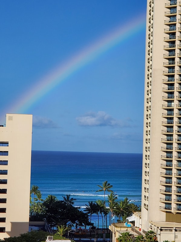 A high-rise hotel with a view of the ocean and a rainbow.