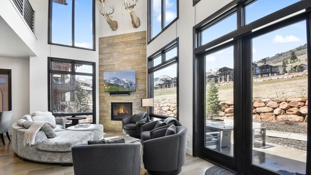 Una sala de estar moderna con chimenea, ventanas amplias y una pared de piedra.