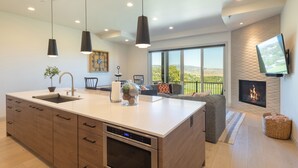 Una cocina moderna con una isla grande, horno empotrado y comedor con vistas al exterior.