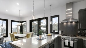 Una cocina moderna con una isla grande, electrodomésticos de acero inoxidable y ventanas amplias que ofrecen vistas al exterior.