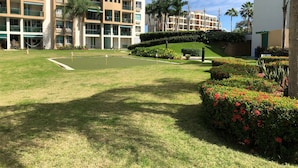A golf course with a putting green, surrounded by well-maintained lawns and flower beds. - Beachfront family friendly garden condo, full A/C, WiFi, sleeps 6, Smart TV's (Cabo Rojo)