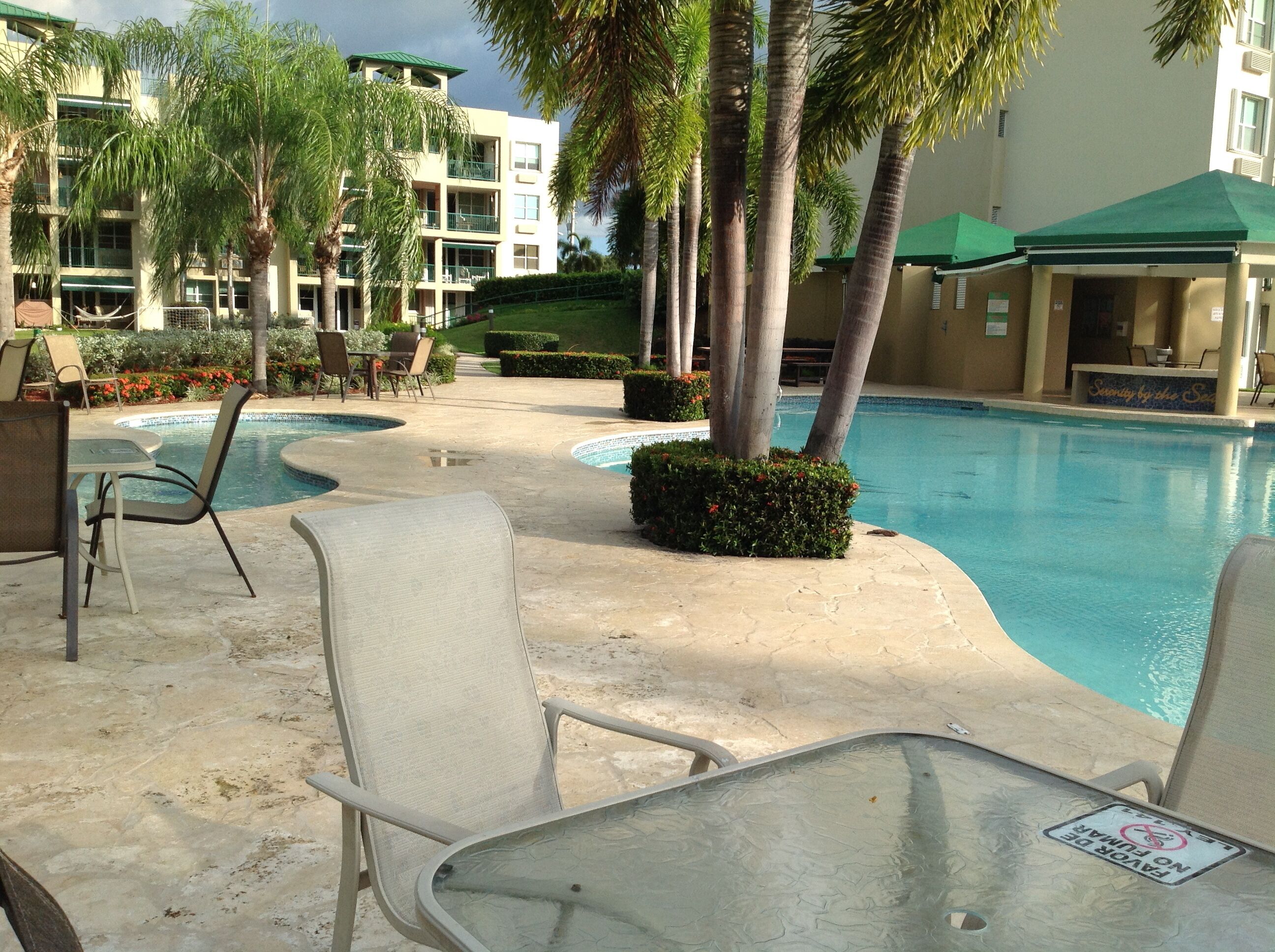 A poolside area with lounge chairs and a sign indicating no umbrellas allowed.
