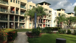 A multi-story hotel with balconies, a central courtyard, and a pathway leading to the entrance. - Beachfront family friendly garden condo, full A/C, WiFi, sleeps 6, Smart TV's (Cabo Rojo)