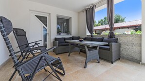 Un espace patio aménagé avec des meubles en osier, une table et une vue sur l’extérieur.