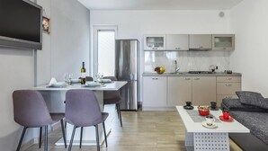 Une cuisine moderne équipée d’un réfrigérateur, d’une cuisinière et de placards. On y trouve également un coin repas avec une table et des chaises.