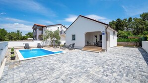Une villa dotée d’une piscine, d’un espace salon extérieur et d’une terrasse couverte.