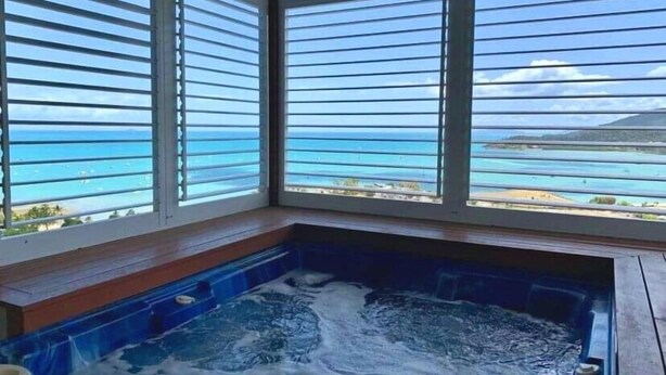 Un jacuzzi con vistas al océano a través de amplios ventanales.