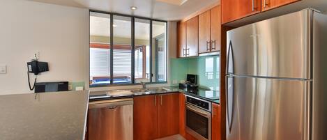 A modern kitchen with wooden cabinets, stainless steel appliances, and a window providing natural light.