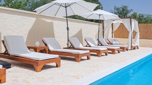 A poolside area with wooden lounge chairs and white canopies. - Awesome home in Sibenik (Sibenik)