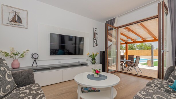 A modern living room with a flat-screen TV, a round coffee table, and a sofa. - Awesome home in Sibenik (Sibenik)