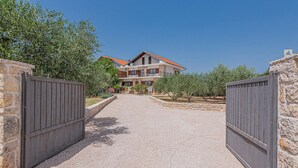 A two-story building with a red-tiled roof, a gravel driveway, and a stone wall. - Awesome home in Sibenik (Sibenik)