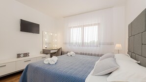 A hotel room with a bed, a desk with a mirror, a television, and a window with sheer curtains. - Awesome home in Sibenik (Sibenik)
