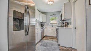 Een moderne keuken met roestvrijstalen apparatuur, witte kasten en betegelde spatwand.