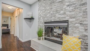 Een moderne woonkamer met een stenen openhaard, een bank en een decoratieve plank.