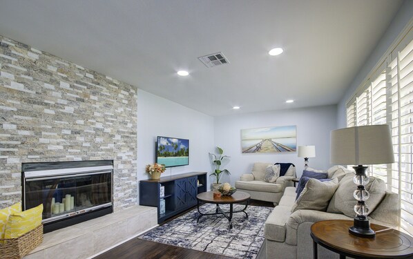 A living room with a stone wall, fireplace, sofa, and coffee table. - Heart of NPB: Your Perfect Home Away from Home! (North Palm Beach)
